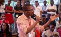 Ung Kenyansk mand med mikrofon, der som en del af et publikum stiller et spørgsmål