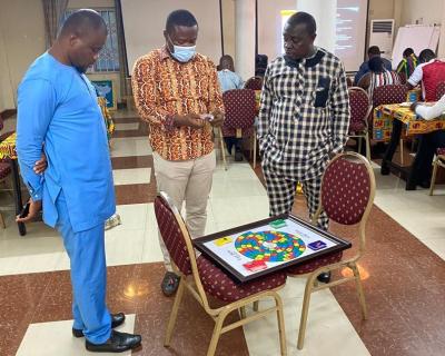 Three men trying the board game in Ghana