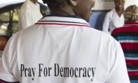 Woman showing the back of her t-shirt saying: Pray for democracy